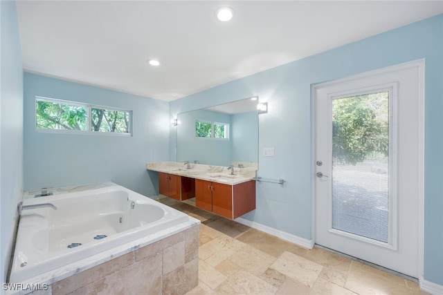 bathroom featuring plenty of natural light, tiled bath, and vanity