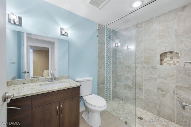 bathroom with vanity, toilet, and a tile shower