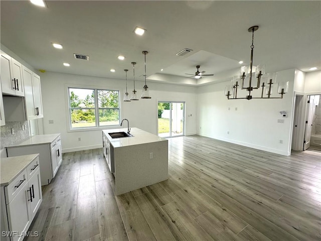 kitchen featuring white cabinetry, sink, pendant lighting, a center island with sink, and ceiling fan with notable chandelier