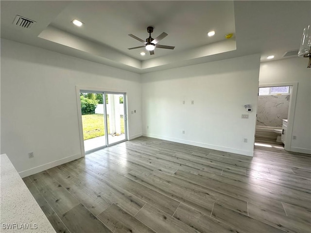 spare room featuring hardwood / wood-style floors, a tray ceiling, and ceiling fan