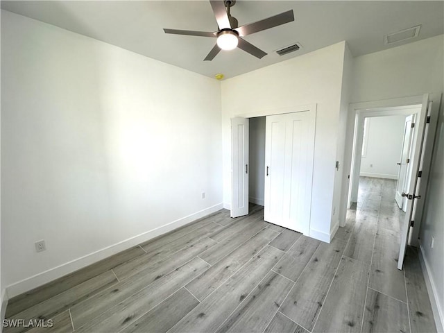 unfurnished bedroom featuring ceiling fan, light hardwood / wood-style floors, and a closet