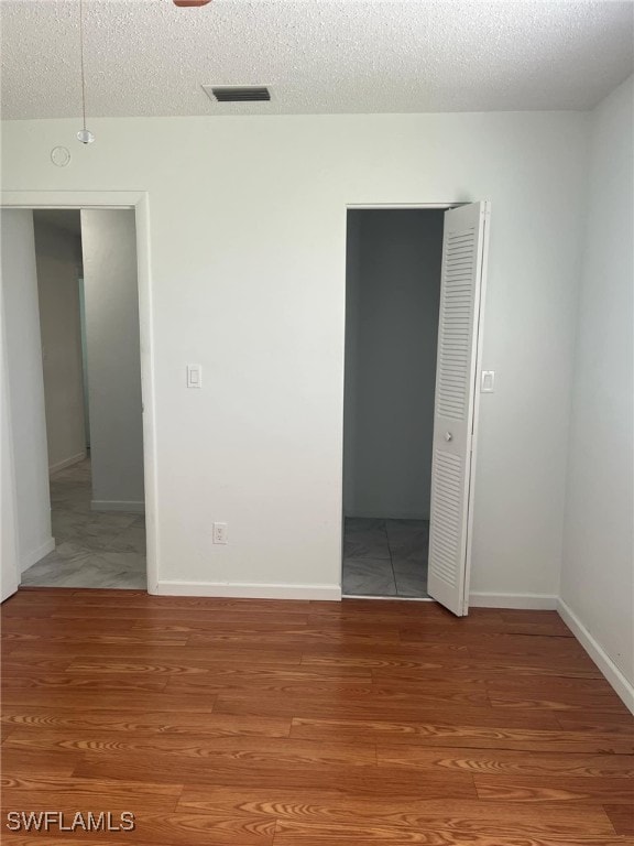 unfurnished bedroom featuring hardwood / wood-style floors and a textured ceiling