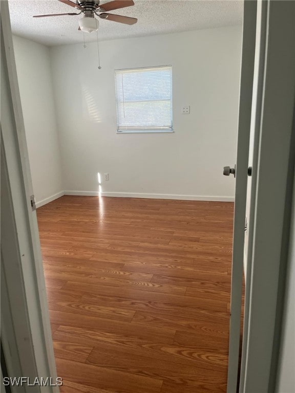 spare room featuring wood-type flooring, a textured ceiling, and ceiling fan