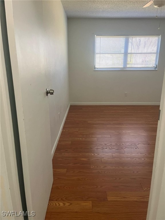 spare room featuring dark hardwood / wood-style flooring, a textured ceiling, and ceiling fan