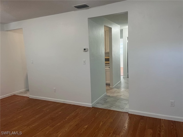 spare room with light hardwood / wood-style floors and a textured ceiling