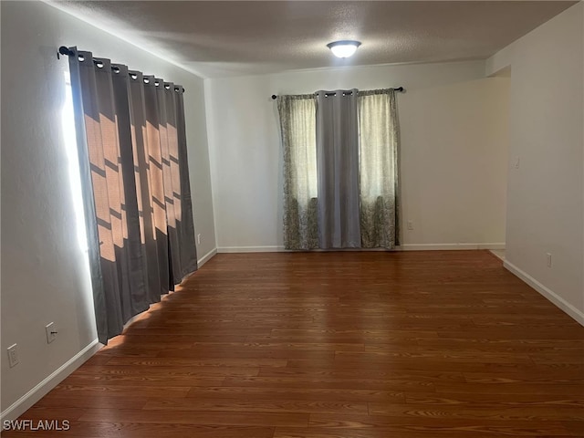 empty room featuring a textured ceiling and dark wood-type flooring