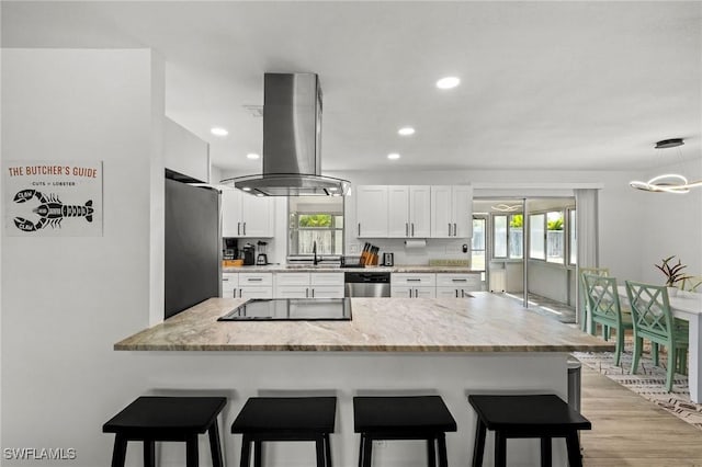 kitchen with white cabinets, sink, light wood-type flooring, appliances with stainless steel finishes, and island exhaust hood