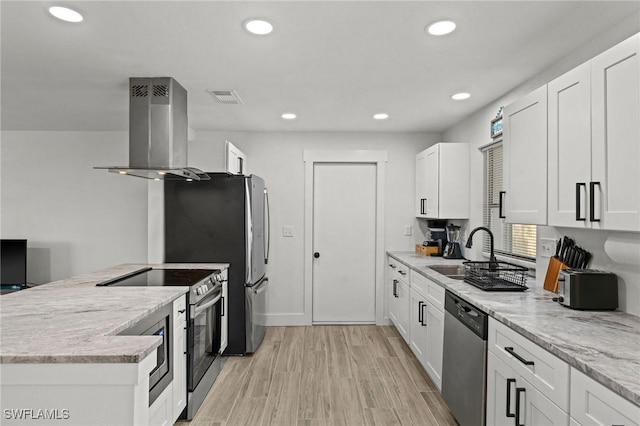 kitchen with sink, stainless steel appliances, wall chimney range hood, light stone counters, and white cabinets