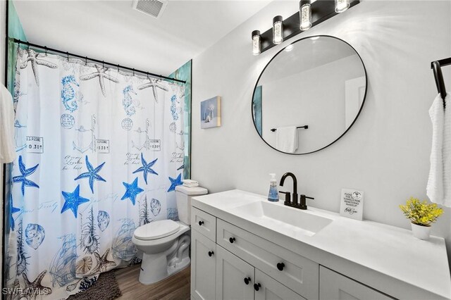 bathroom with hardwood / wood-style flooring, vanity, toilet, and walk in shower