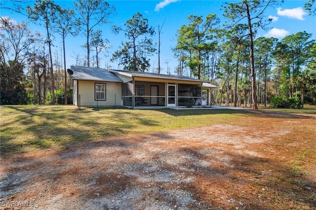 back of property with a sunroom and a lawn