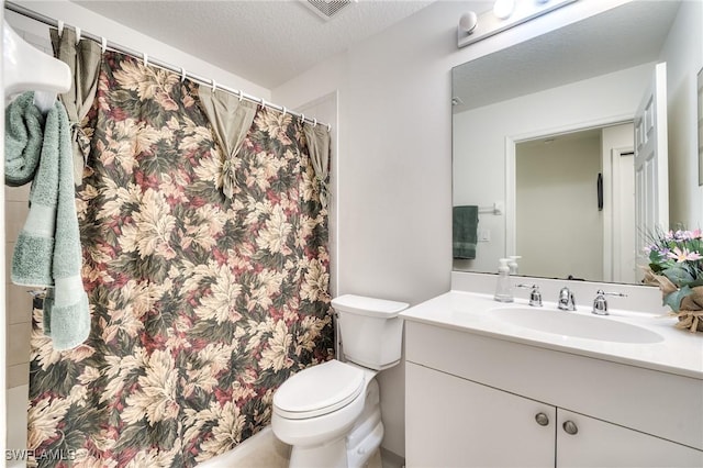 bathroom with vanity, toilet, and a textured ceiling