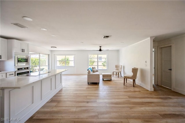 kitchen with white cabinets, ceiling fan, stainless steel appliances, and light hardwood / wood-style flooring