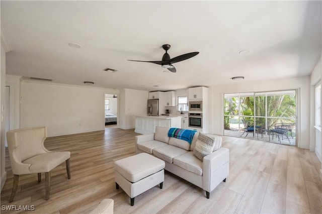 living room with ceiling fan, light wood-type flooring, and sink