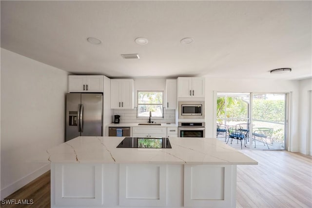 kitchen with tasteful backsplash, light stone counters, stainless steel appliances, sink, and white cabinetry