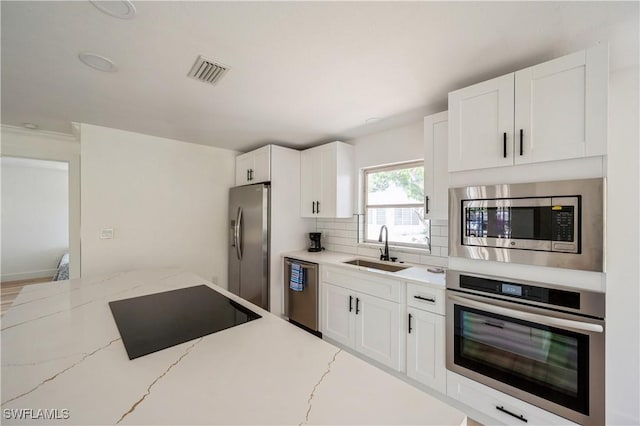 kitchen featuring white cabinetry, light stone counters, sink, and stainless steel appliances