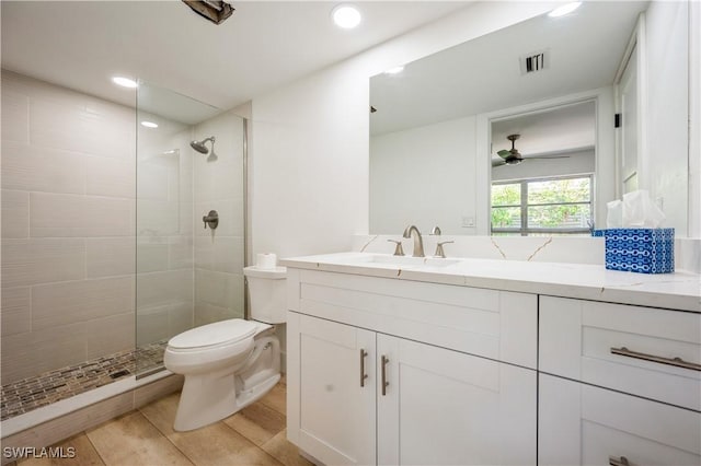 bathroom featuring vanity, ceiling fan, toilet, and a tile shower