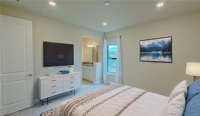 bedroom with ensuite bathroom and light carpet