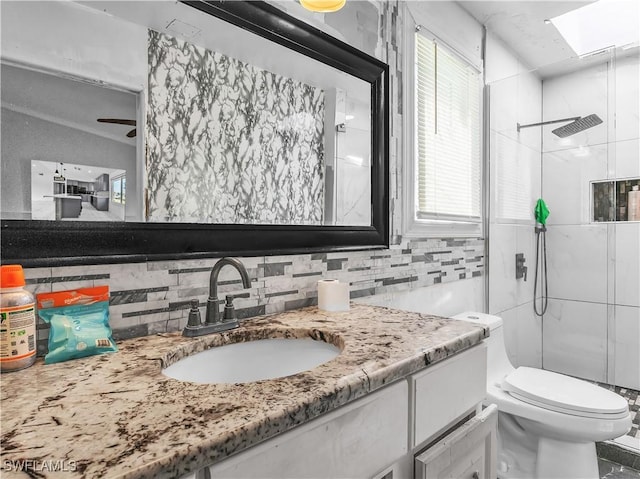 bathroom with backsplash, a skylight, vanity, toilet, and walk in shower