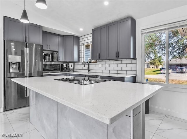 kitchen with a kitchen island, decorative backsplash, hanging light fixtures, light stone counters, and stainless steel refrigerator with ice dispenser