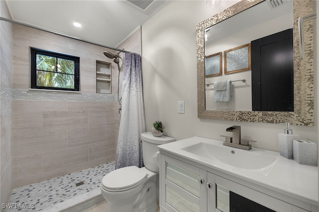 bathroom featuring visible vents, tiled shower, vanity, and toilet