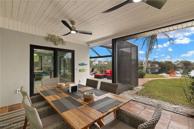 view of patio featuring a water view, glass enclosure, and ceiling fan