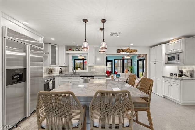 kitchen with white cabinetry, backsplash, and built in appliances