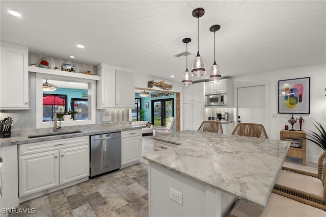 kitchen featuring white cabinets, decorative backsplash, appliances with stainless steel finishes, a breakfast bar, and a sink