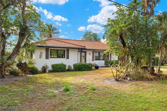 view of front of house with a front yard, a tile roof, and stucco siding