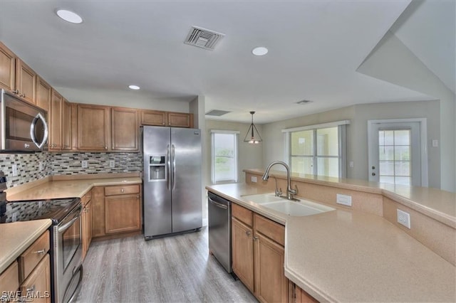 kitchen with a healthy amount of sunlight, pendant lighting, light wood-type flooring, and appliances with stainless steel finishes