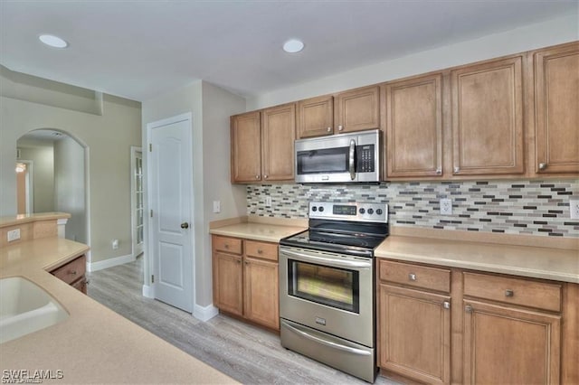 kitchen featuring light wood-type flooring, backsplash, and stainless steel appliances