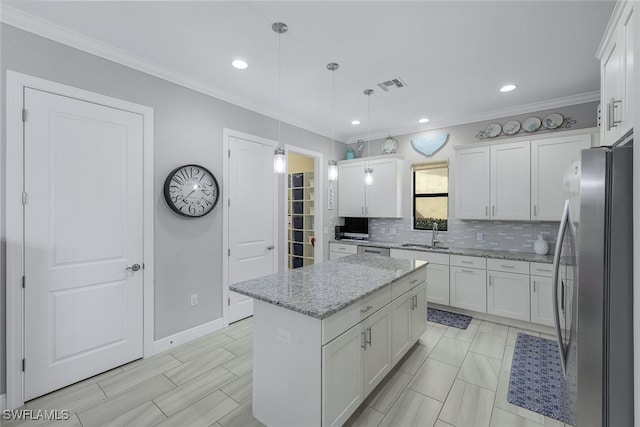 kitchen featuring light stone counters, stainless steel fridge, a kitchen island, and white cabinets