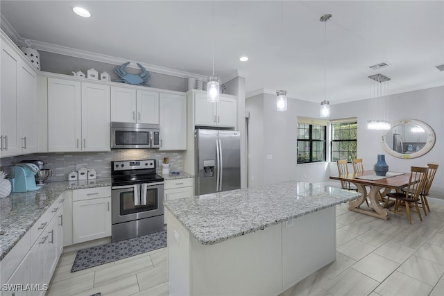 kitchen with decorative light fixtures, a kitchen island, stainless steel appliances, decorative backsplash, and white cabinets