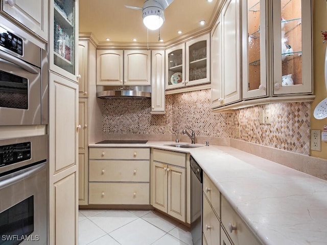 kitchen with appliances with stainless steel finishes, backsplash, sink, light tile patterned floors, and cream cabinets