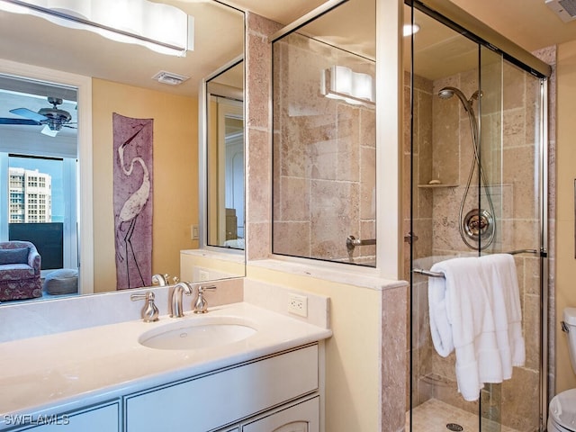 bathroom featuring vanity, ceiling fan, toilet, and a shower with door