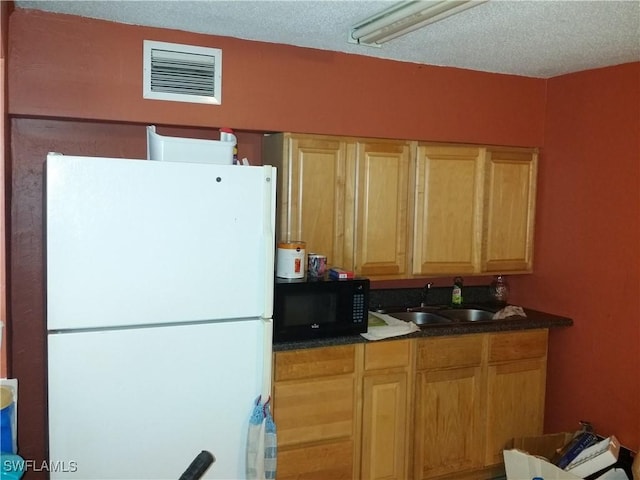 kitchen with sink, a textured ceiling, and white refrigerator