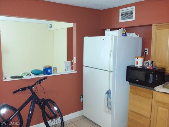 kitchen with light brown cabinetry, light tile patterned flooring, and white refrigerator