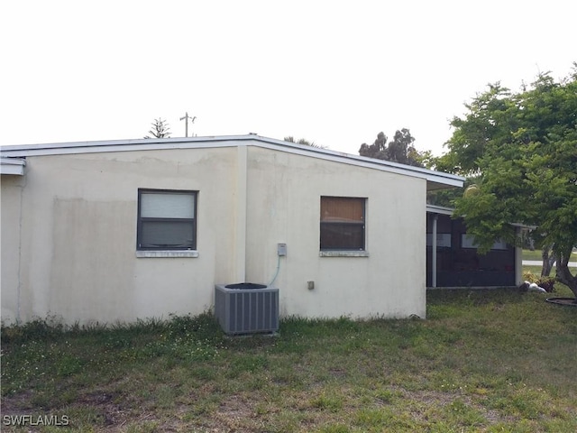 view of side of property with a lawn and central air condition unit