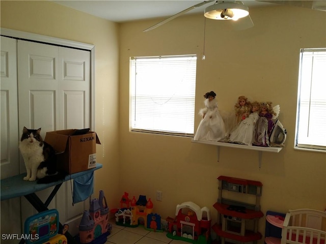 bedroom with ceiling fan, light tile patterned flooring, and a closet