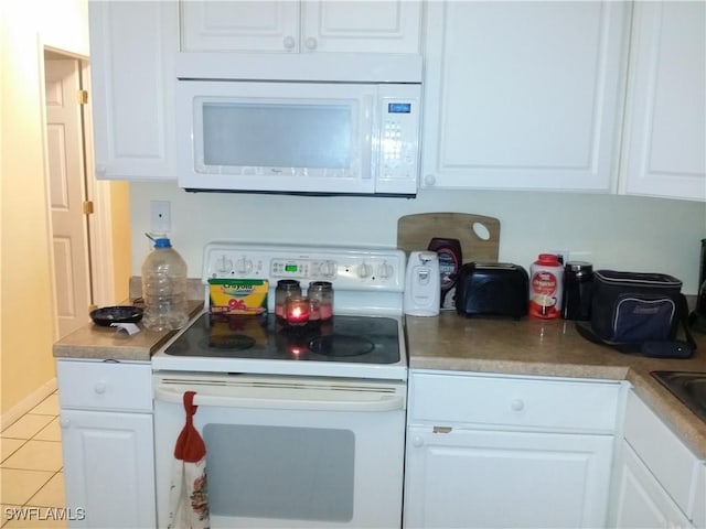 kitchen with white cabinets, light tile patterned flooring, and white appliances