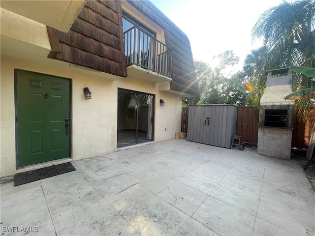 view of patio / terrace with an outdoor structure, a storage unit, and fence