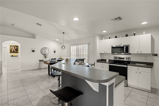 kitchen with white cabinets, appliances with stainless steel finishes, decorative light fixtures, and lofted ceiling