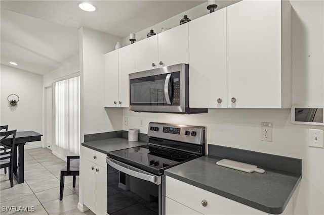 kitchen with a wealth of natural light, light tile patterned floors, white cabinetry, and appliances with stainless steel finishes