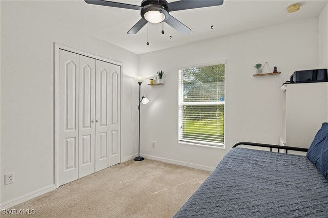 bedroom featuring ceiling fan, a closet, and light colored carpet