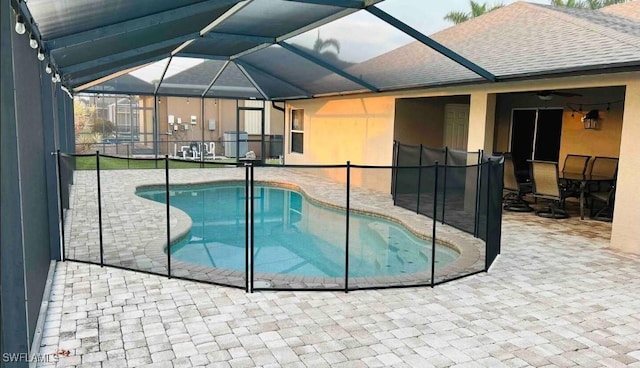 view of swimming pool featuring glass enclosure and a patio area