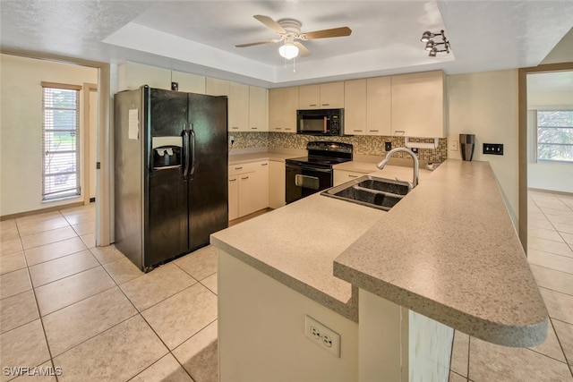 kitchen with black appliances, sink, kitchen peninsula, a raised ceiling, and plenty of natural light