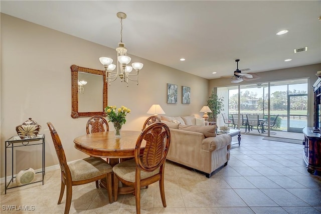 tiled dining room with ceiling fan with notable chandelier