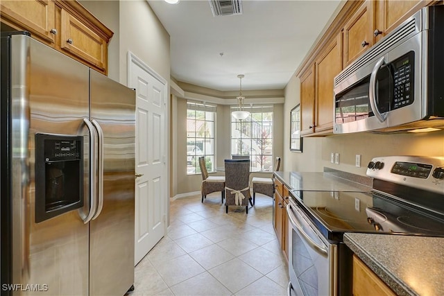 kitchen with hanging light fixtures, light tile patterned floors, and stainless steel appliances