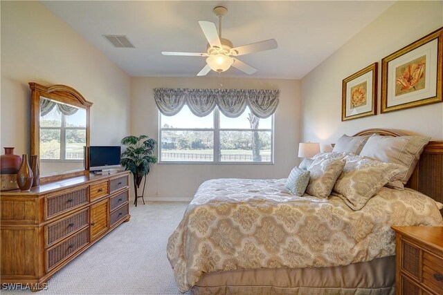 bedroom featuring ceiling fan, light carpet, and multiple windows