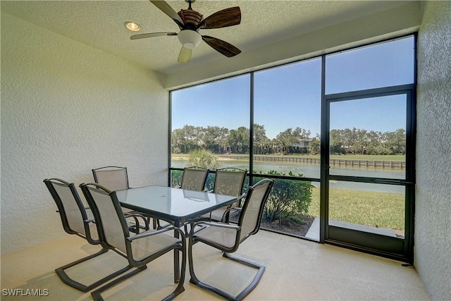 sunroom / solarium featuring a water view and ceiling fan