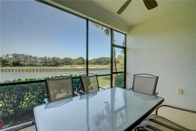 sunroom with ceiling fan and a water view